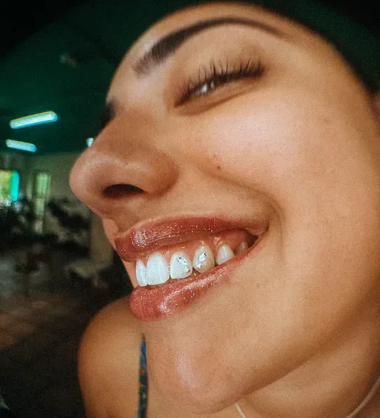 Un primer plano del rostro de una mujer sonriendo con los ojos cerrados.