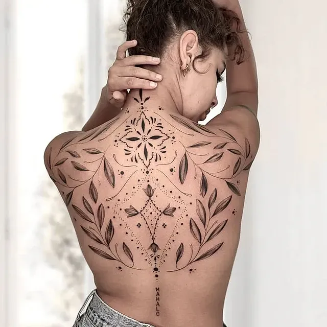 Una mujer tiene un tatuaje en la espalda que parece un diseño floral.