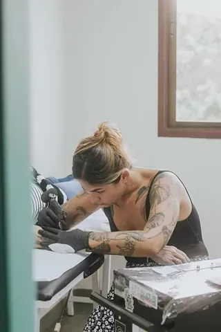 Una mujer se hace un tatuaje en el brazo en una habitación.