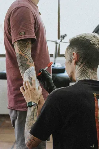 Un hombre se hace un tatuaje en el brazo hecho por un tatuador.