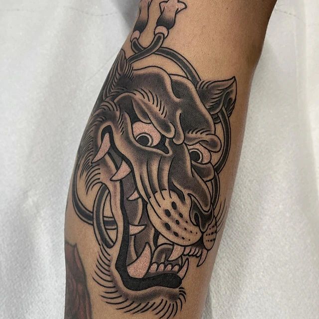 Un tatuaje en blanco y negro de un tigre en la pierna de una persona.