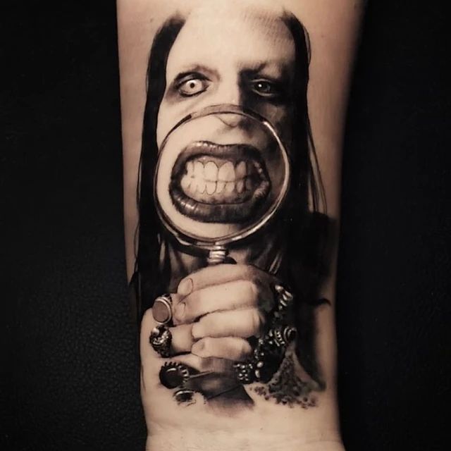 Un tatuaje en blanco y negro de una mujer sosteniendo una lupa.