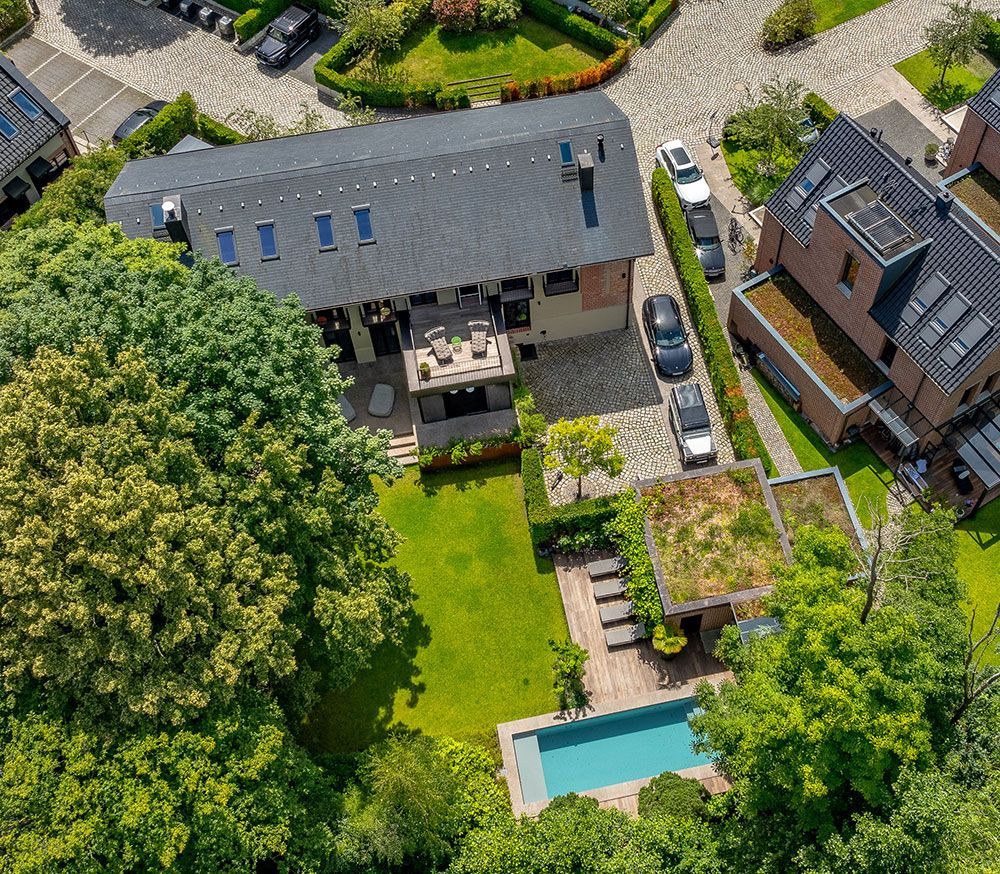 Luftaufnahme eines Hauses mit Pool, Garten und Gründach.