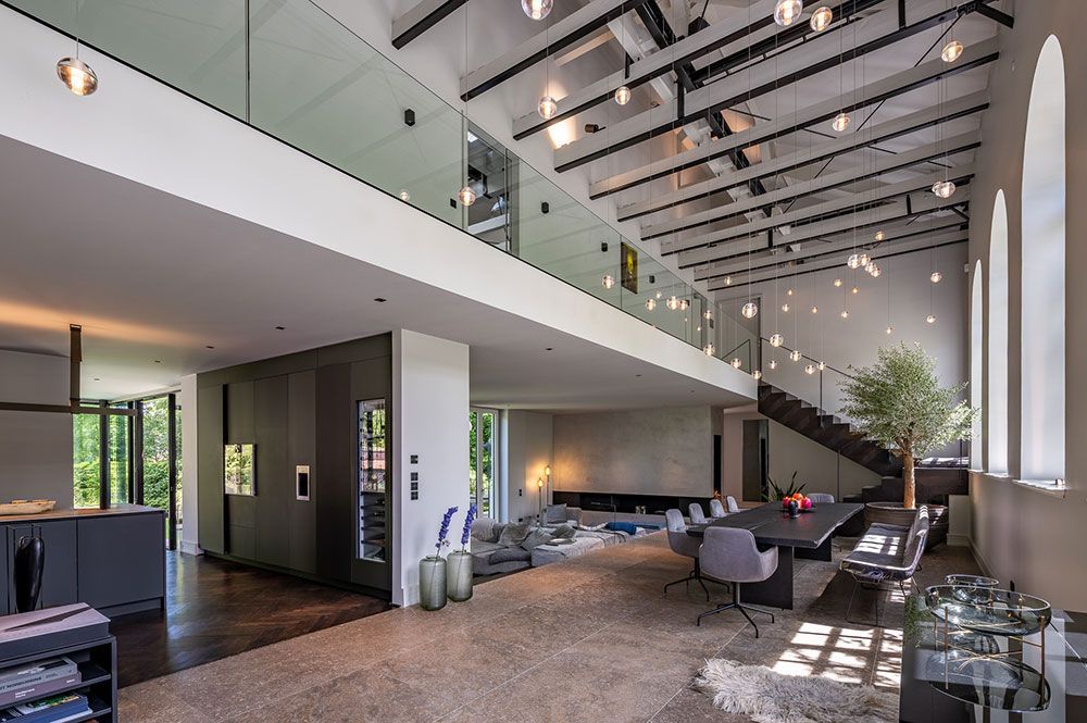 Großzügiges, modernes Interieur mit Galerie. Verfügt über einen Essbereich, ein Treppenhaus und große Fenster.