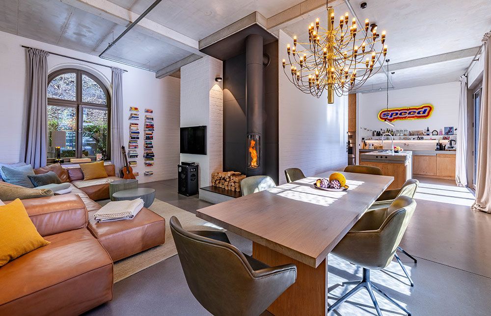 Offener Wohnbereich mit Kamin, Essbereich, Küche und großen Fenstern.