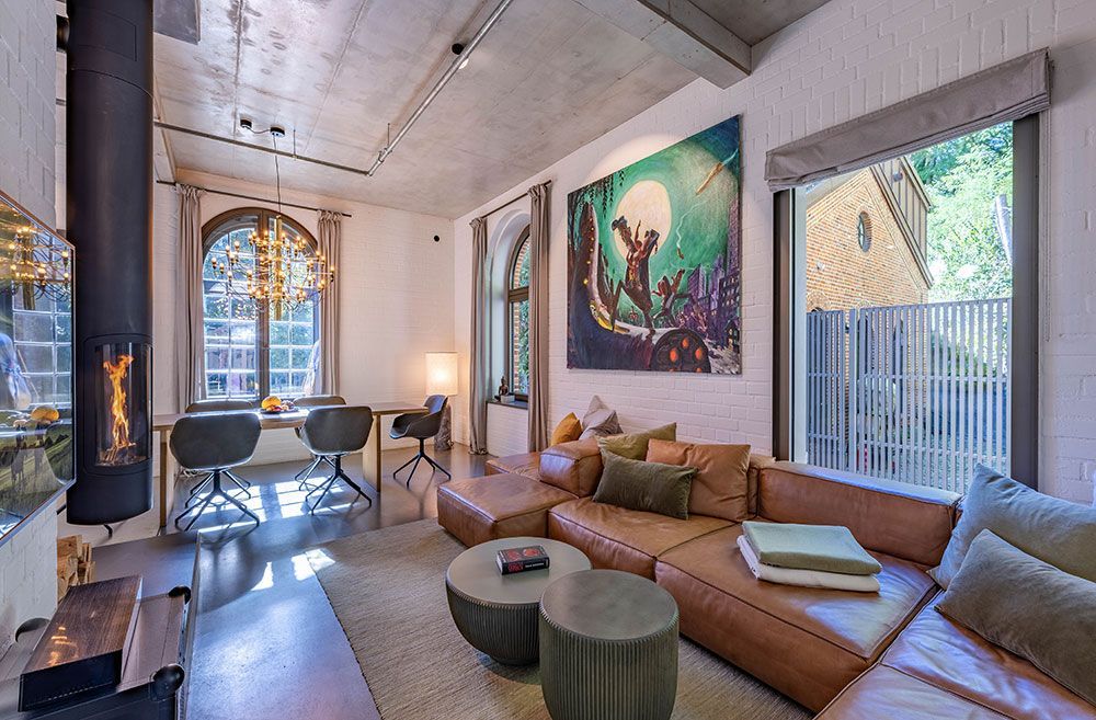 Modernes Wohnzimmer mit Ledersofa, Kamin, Bogenfenstern und Kunstwerken.