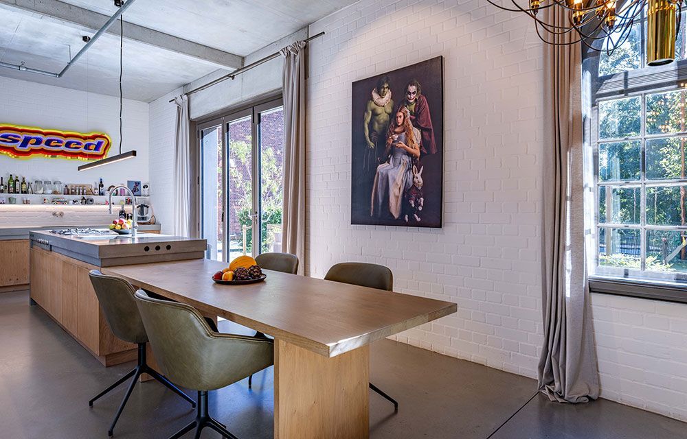 Moderner Essbereich mit Tisch, Stühlen, Kunstwerken und großen Fenstern mit grauen Vorhängen.