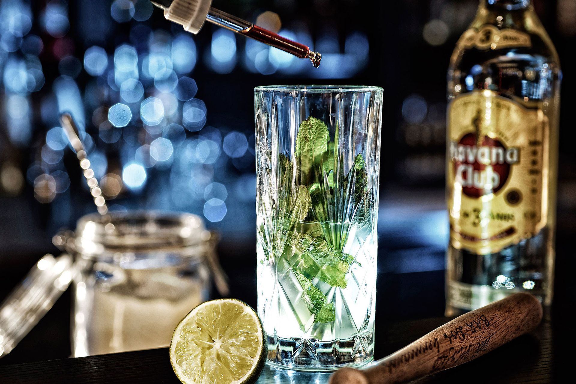 Zubereitung des Cocktails: Ein hohes Glas mit Minze, Limette und einer Rumflasche auf der Bar bereitstellen; mit einer Pipette Flüssigkeit hinzufügen.