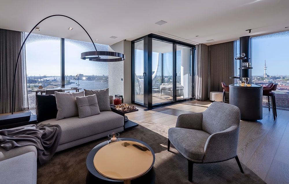 Modernes Wohnzimmer mit Stadtblick, grauen Möbeln, großen Fenstern und einer runden Bar.