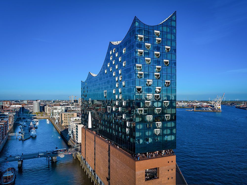 Elbphilharmonie, Hamburg, Deutschland, moderne Glasfassade auf einem Backsteinsockel, direkt am Wasser.