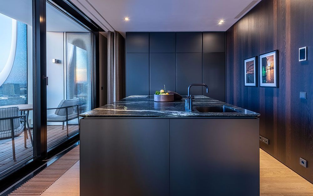 Moderne Küche mit dunklen Schränken, großer Kochinsel und Balkonblick.