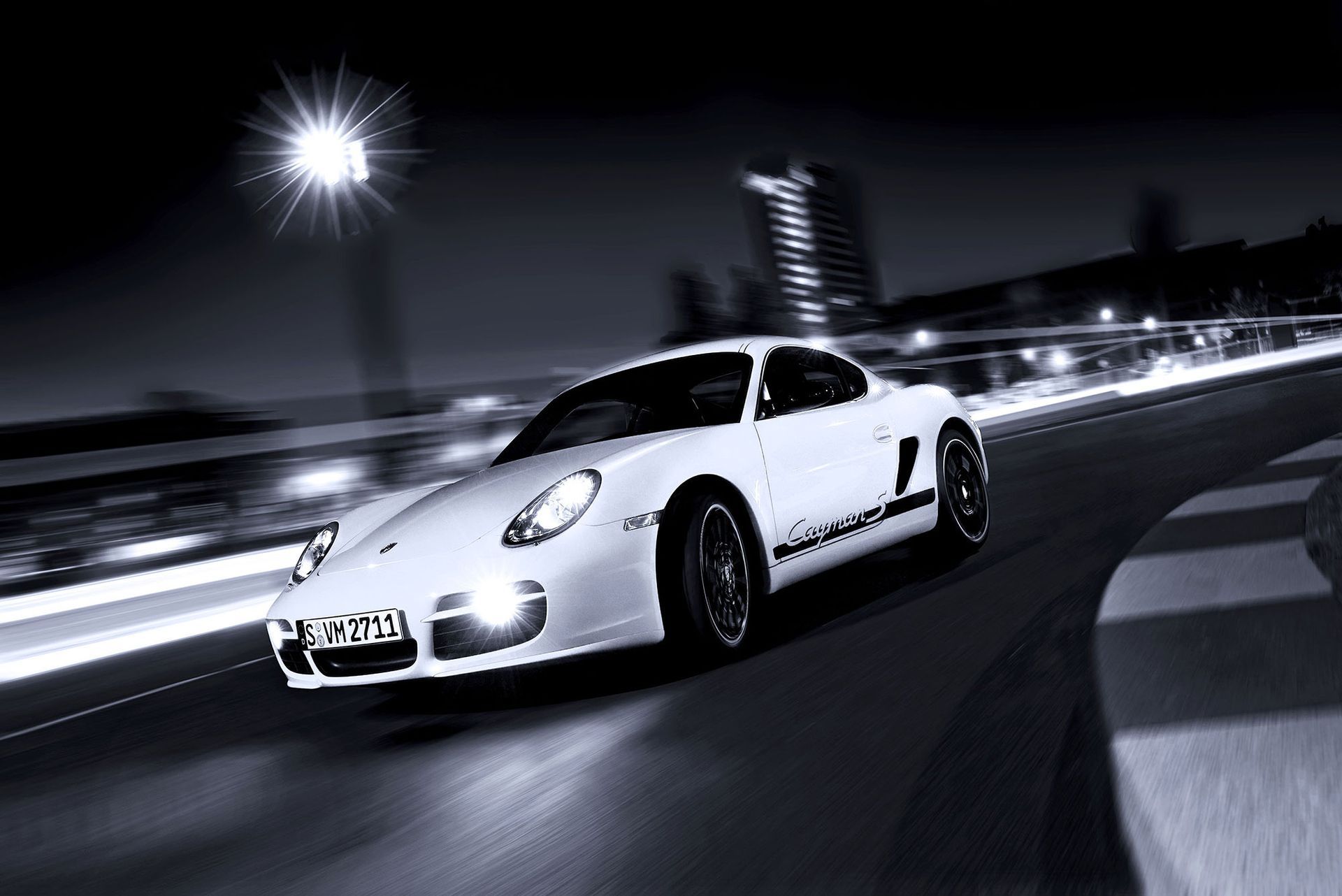 Ein weißer Porsche-Sportwagen fährt nachts auf einer Rennstrecke; die Bewegung ist verschwommen.
