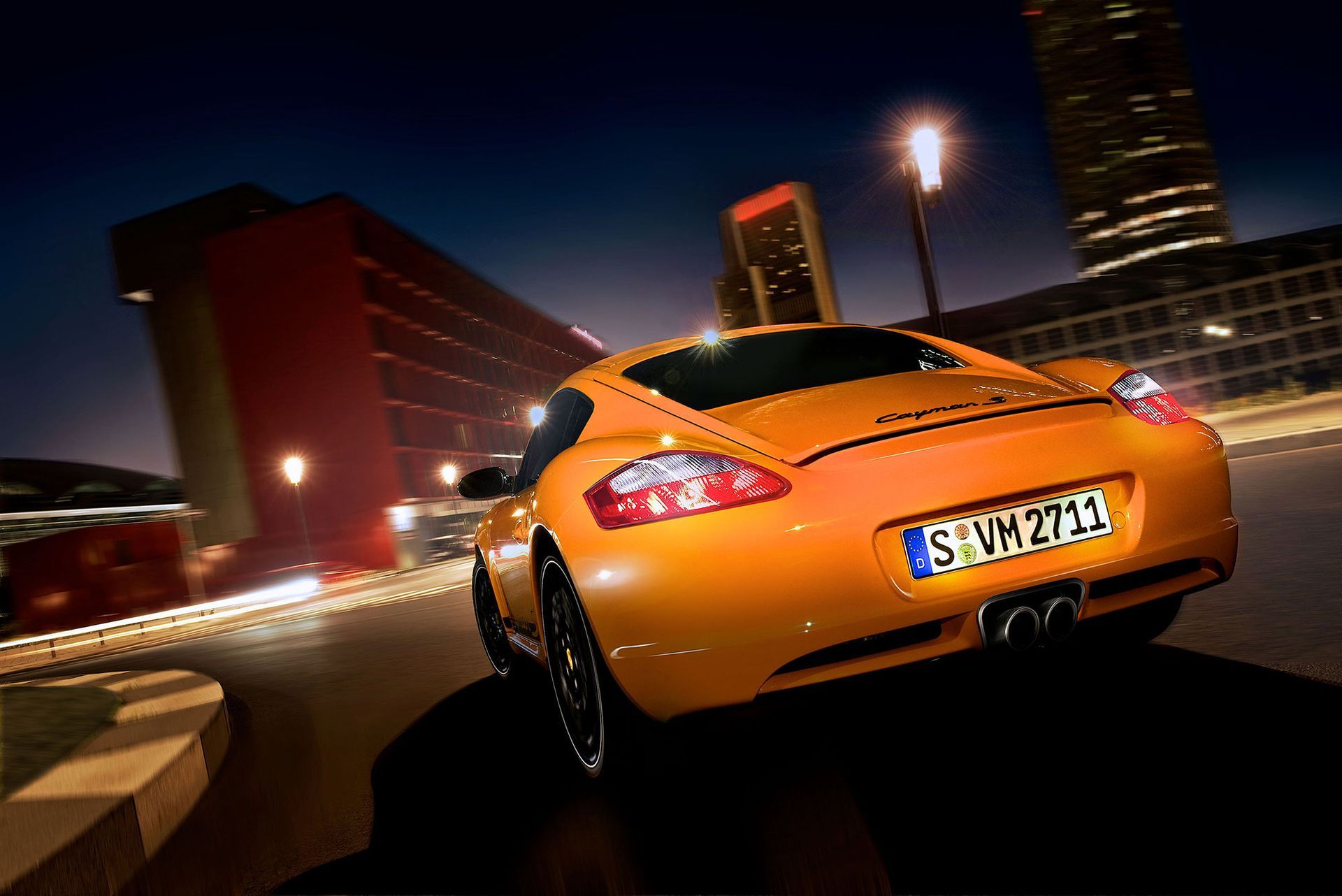 Ein orangefarbener Porsche-Sportwagen fährt nachts auf einer Stadtstraße.