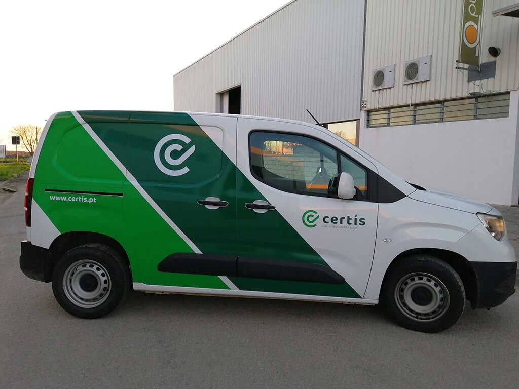 Uma van verde e branca está estacionada em frente a um prédio.