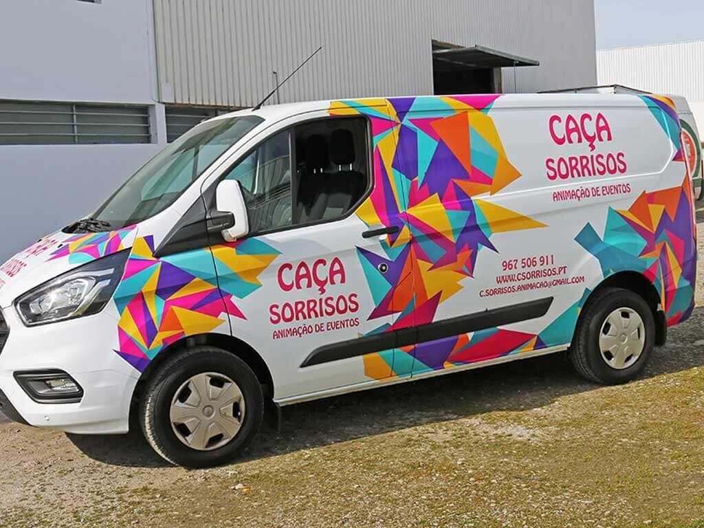 Uma van colorida está estacionada em frente a um prédio.