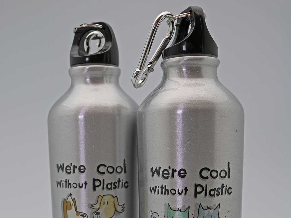 Duas garrafas de água prateadas que dizem que somos legais sem plástico
