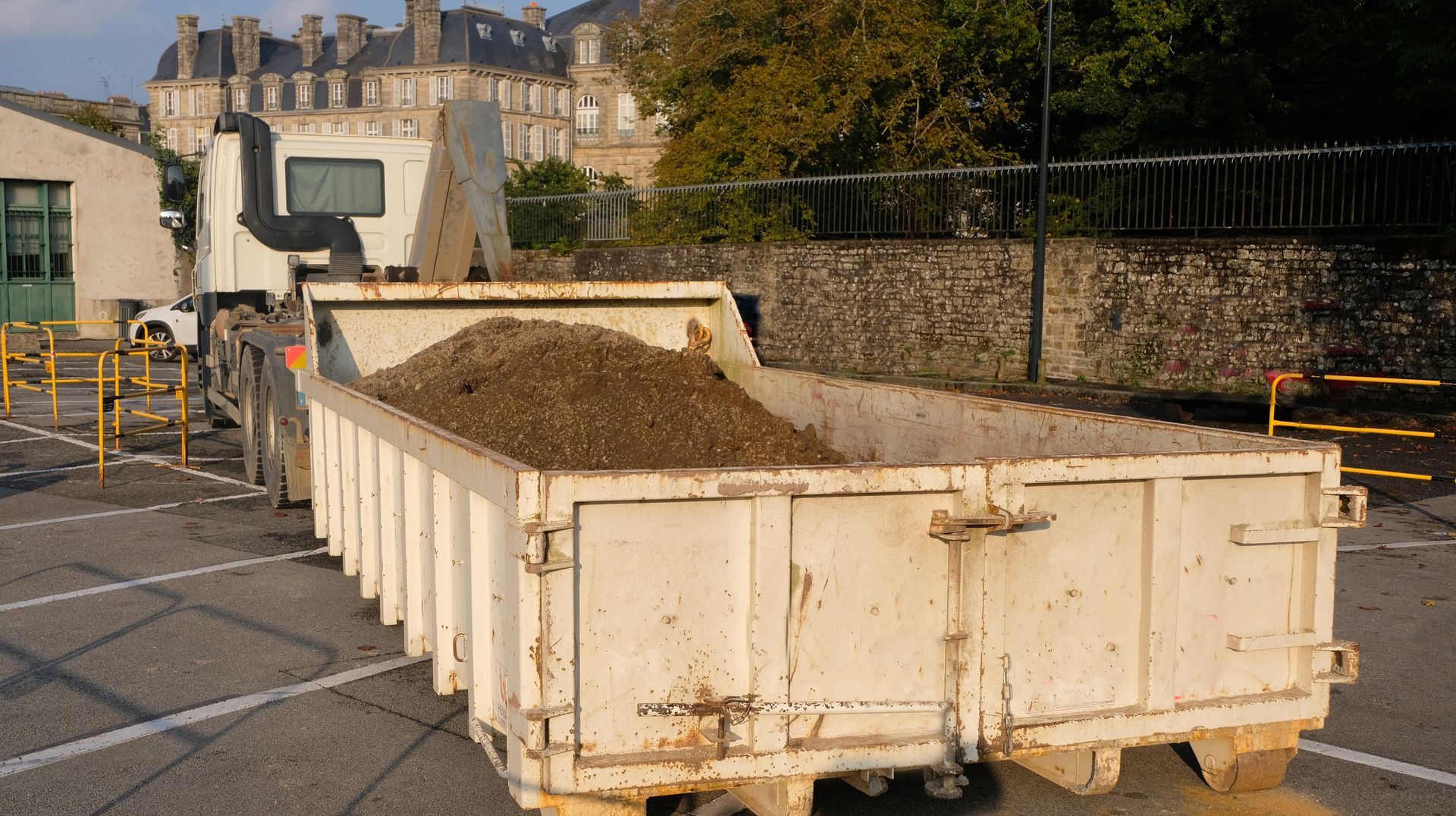 Camion à benne remplie de terre sur un parking.