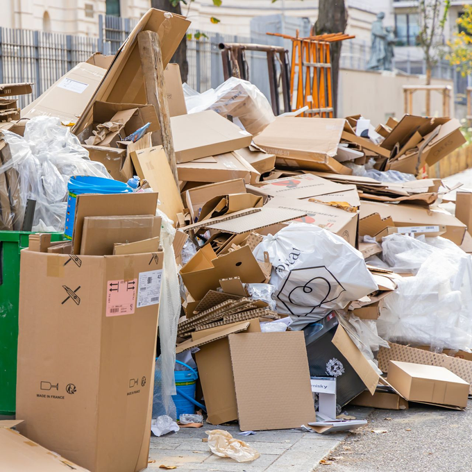 Un amas de cartons, de sacs et de débris déborde sur un trottoir de la ville.
