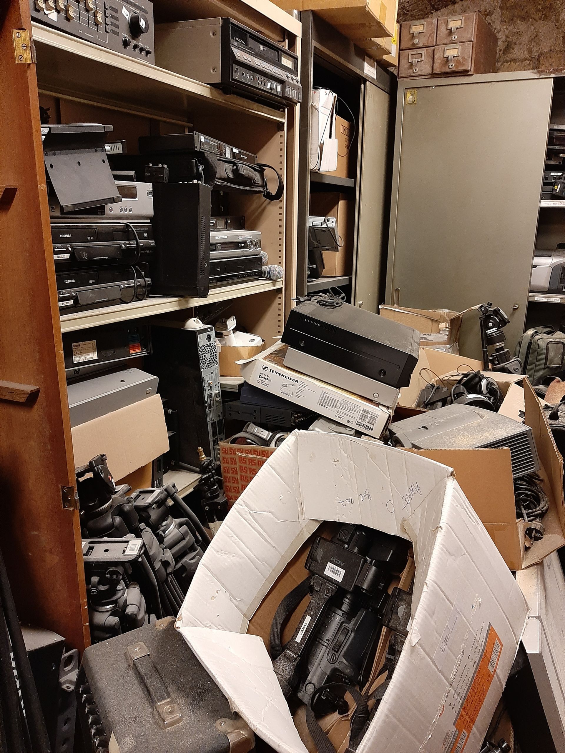 Pièce de stockage en désordre, remplie d'appareils et d'équipements électroniques.