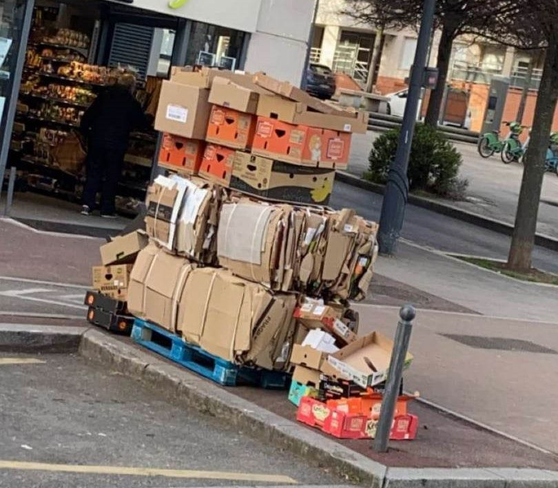 Des cartons empilés sur une palette en bordure de trottoir.