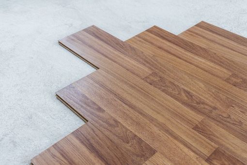 Auf einem Teppichboden wird ein Holzboden verlegt.