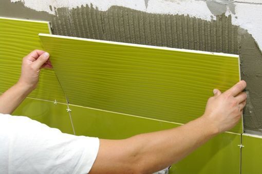 Ein Mann bringt grüne Fliesen an einer Wand an.