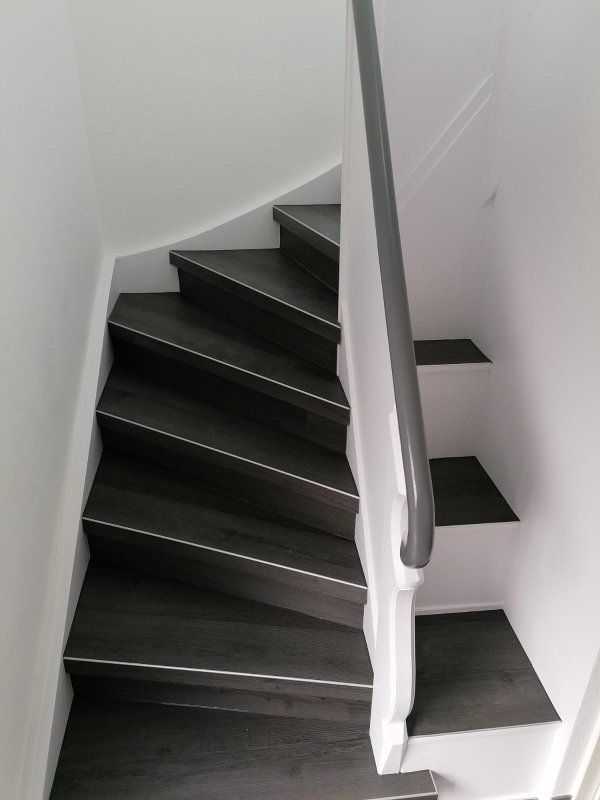 Eine Treppe mit weißem Geländer und schwarzen Stufen