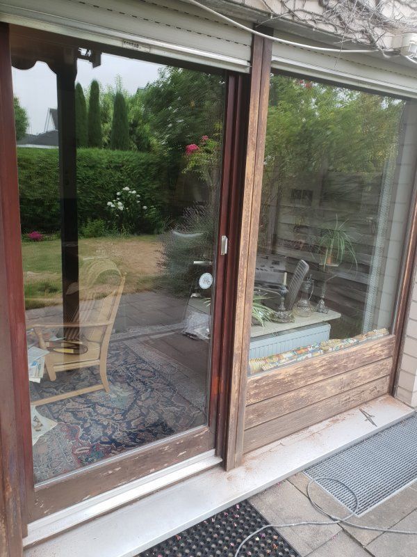 Eine Glasschiebetür mit der Spiegelung einer Terrasse im Fenster.