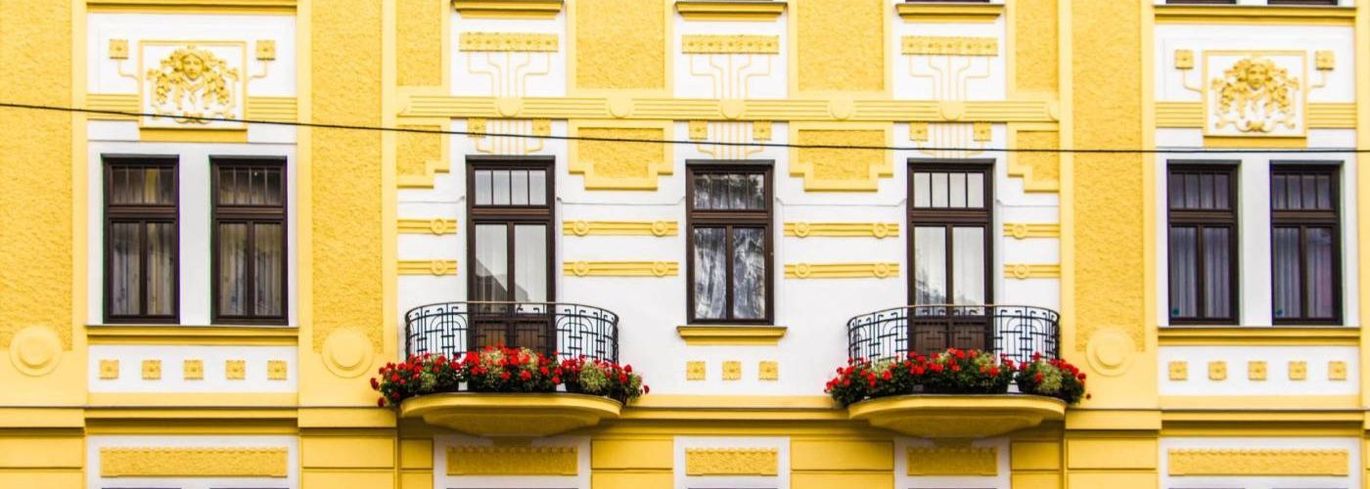 Ein gelbes Gebäude mit einem Balkon und Blumen darauf.