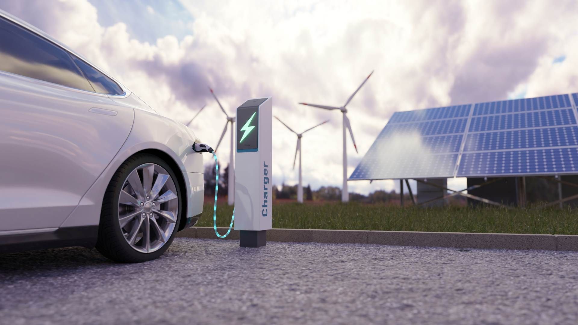 An einer Ladestation wird ein Elektroauto aufgeladen, im Hintergrund sind Solarmodule und Windräder zu sehen.