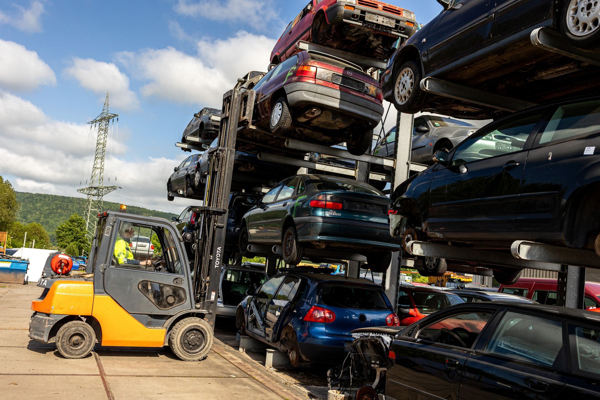 Ein Gabelstapler transportiert einen Stapel Autos auf einem Schrottplatz.