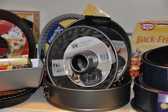 Pfannen und Kochgeschirr, darunter ein großer Pfannendeckel, auf einem Ausstellungstisch