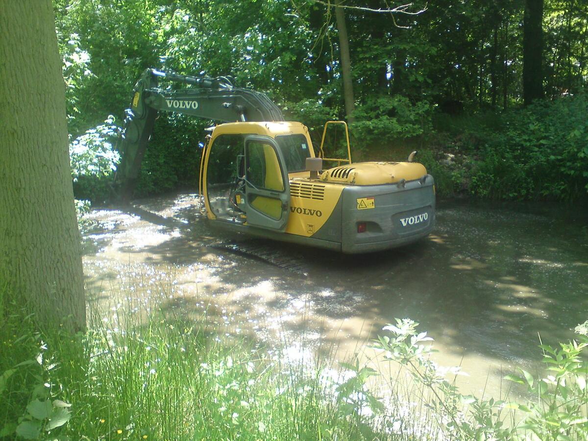 Dragage d'un étang avec une tractopelle jaune