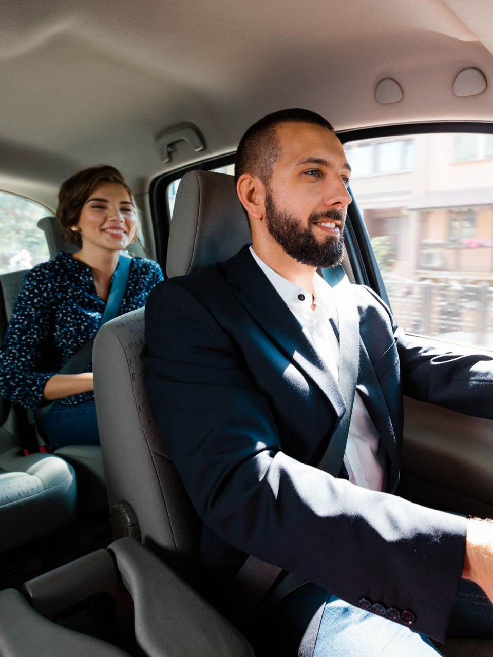 Un homme conduit une voiture avec un passager à l'arrière.