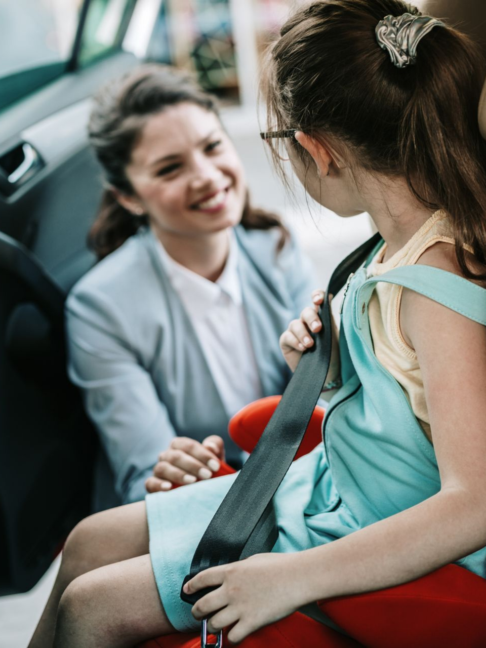 Une femme sourit à son enfant installé dans son siège auto.