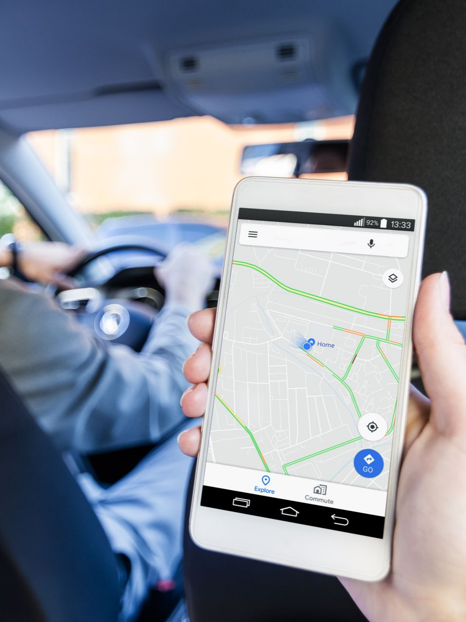 Une personne tenant un téléphone avec une application de cartographie visible dans une voiture.