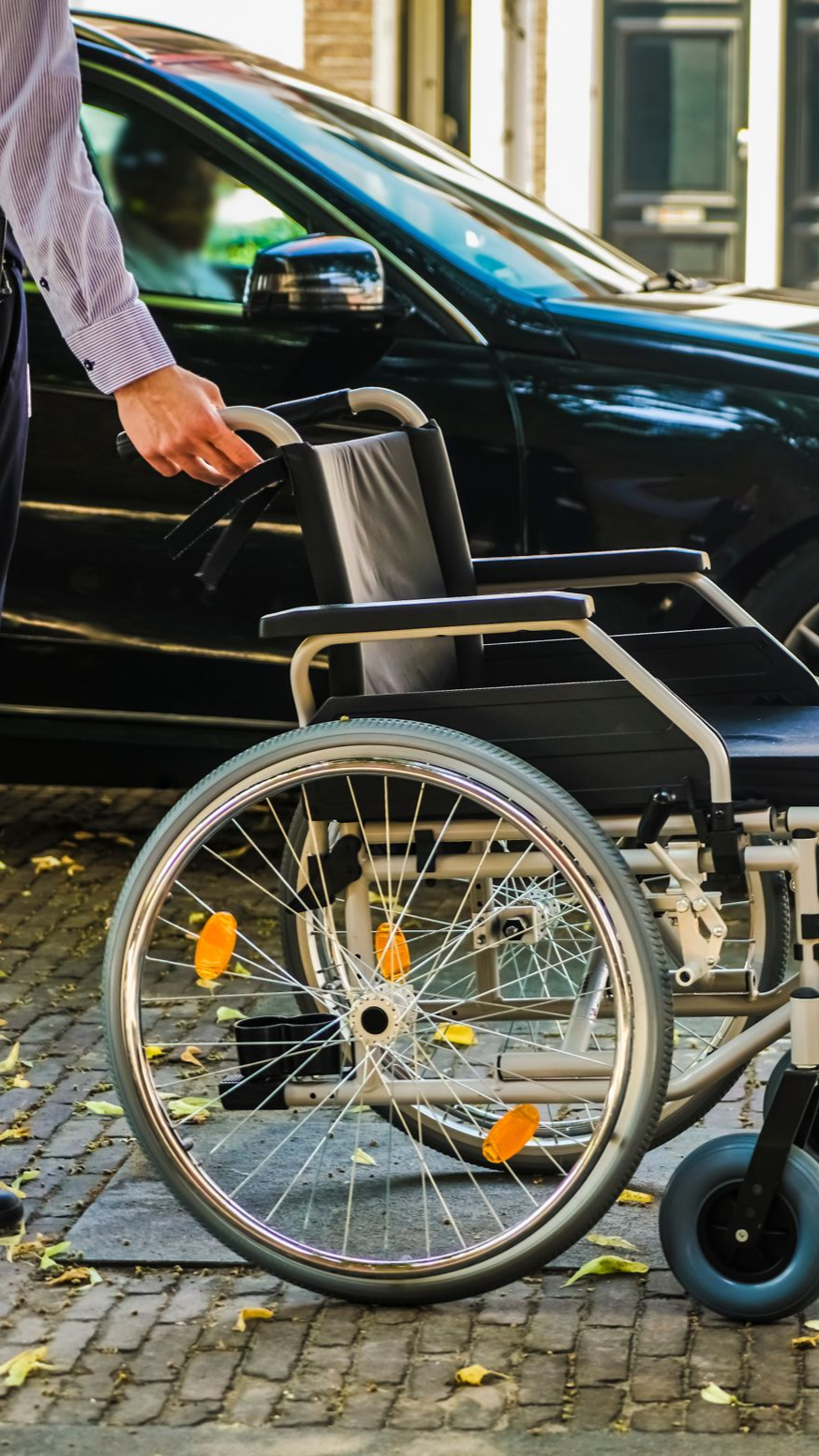 Une personne avec un fauteuil roulant se trouve près d'une voiture.