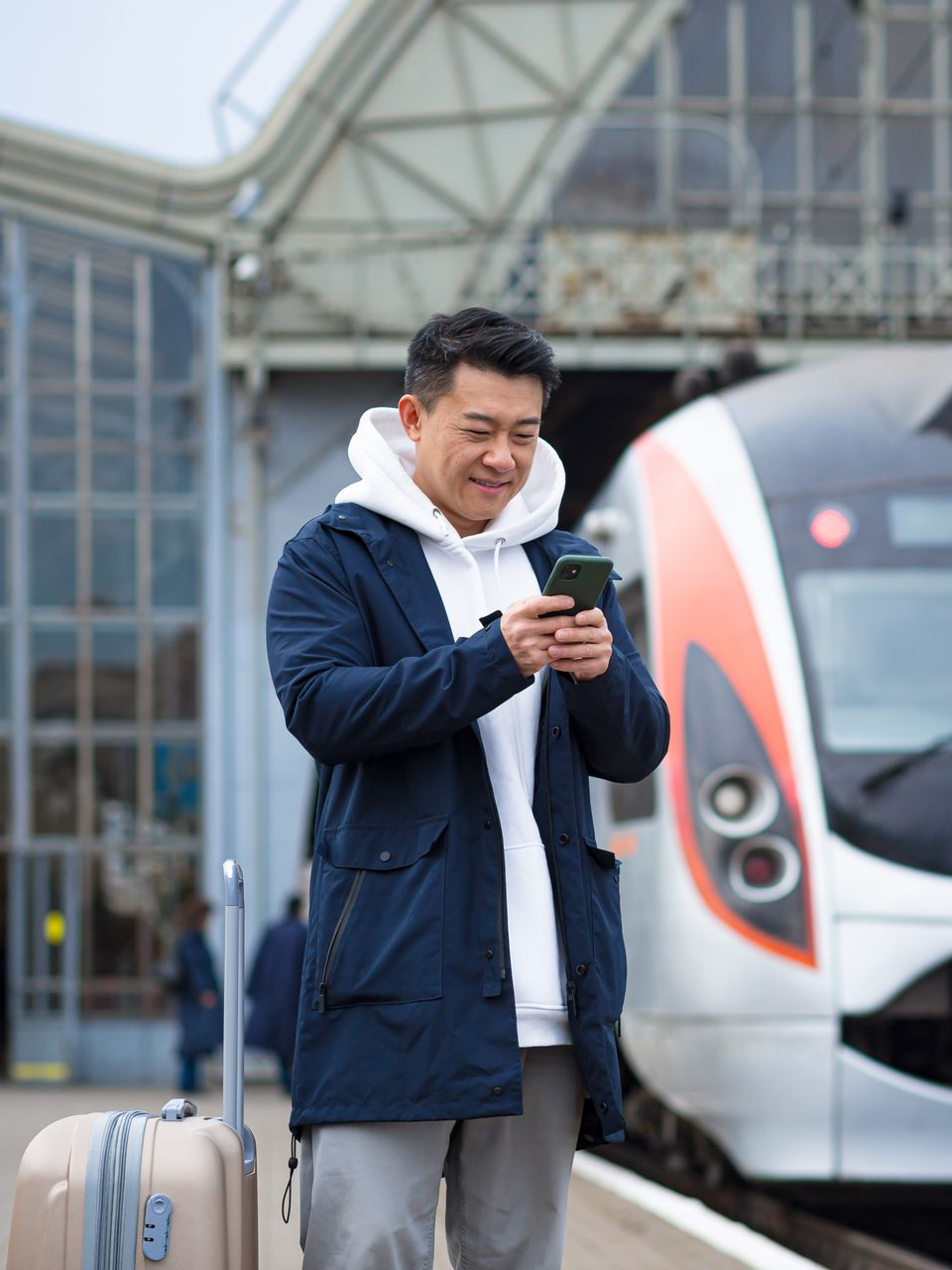 Un homme regarde son téléphone dans une gare.