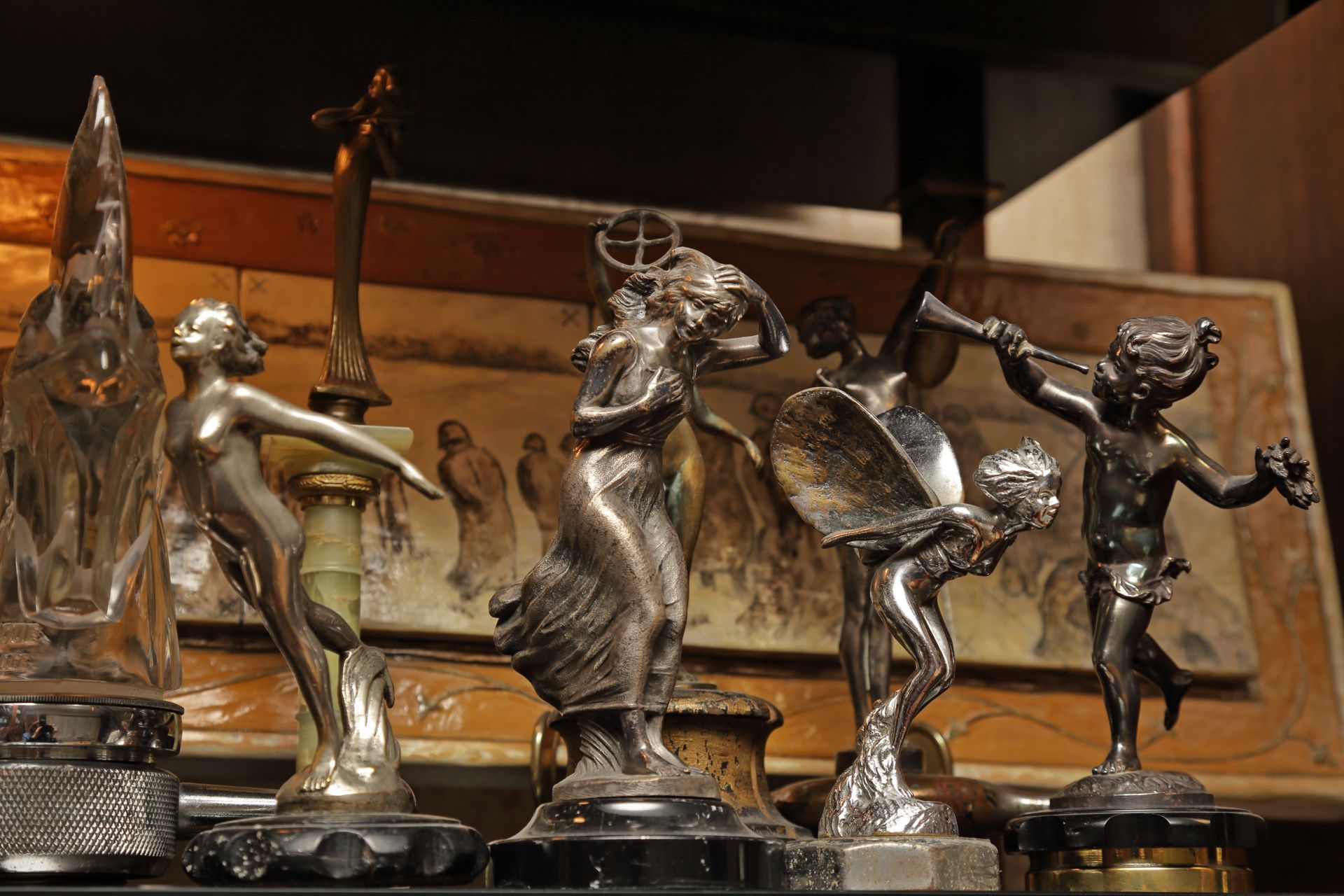 Étagère de petites figurines de danseuses en argent et de trophées présentés dans une vitrine en bois.