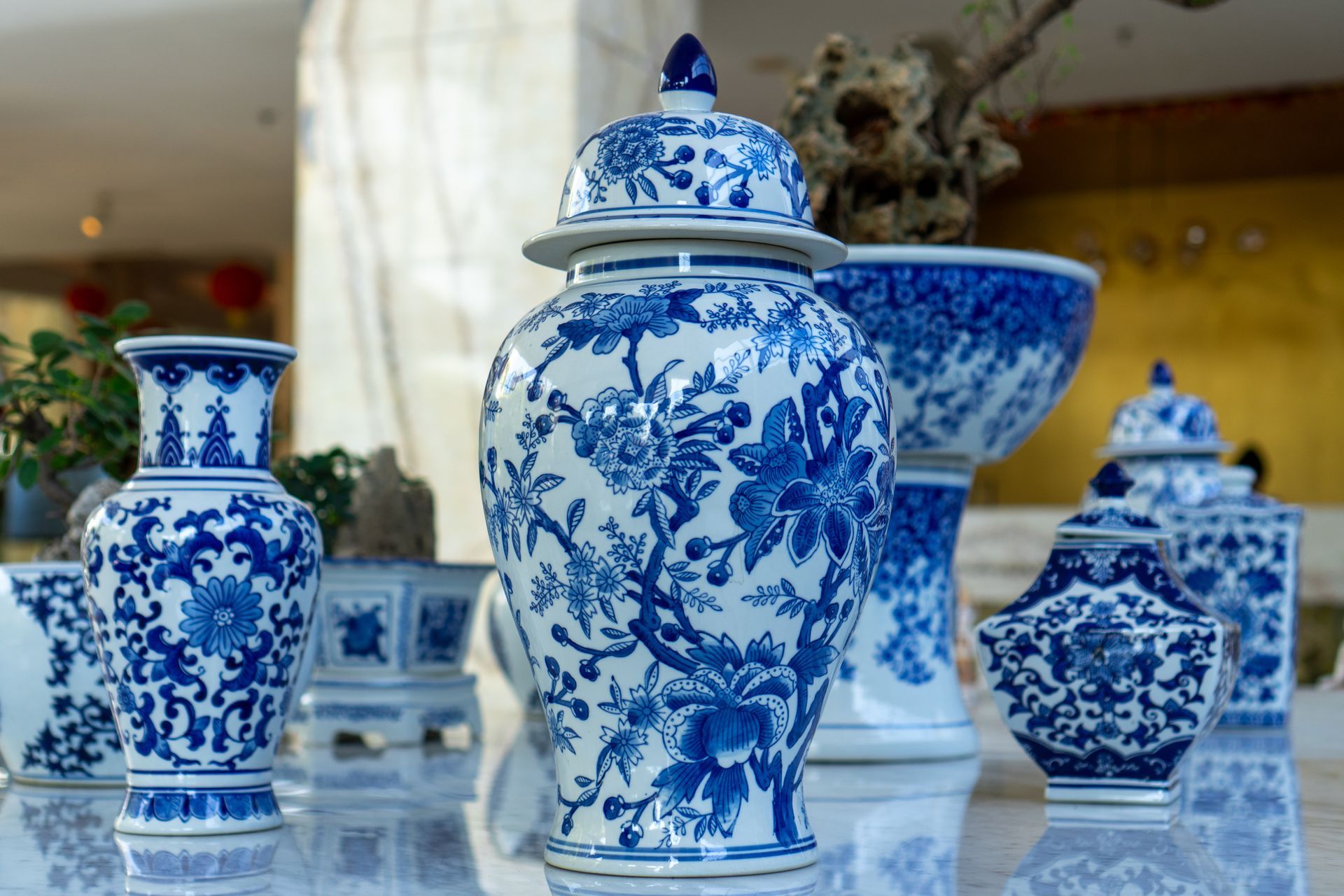 Vases et pots en porcelaine bleue et blanche exposés sur une surface réfléchissante.
