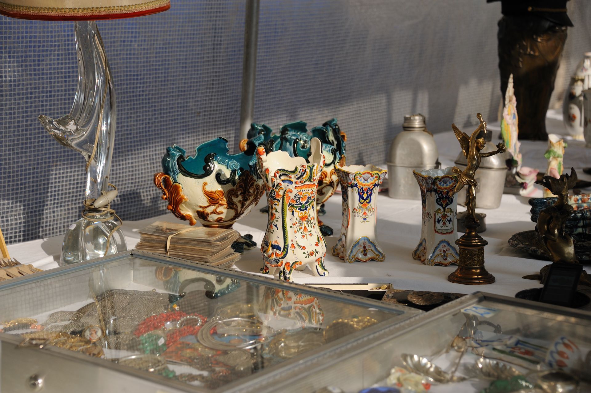 Présentoir sous verre de figurines en céramique colorées et d'objets décoratifs sur des étagères dans un magasin ou une galerie.