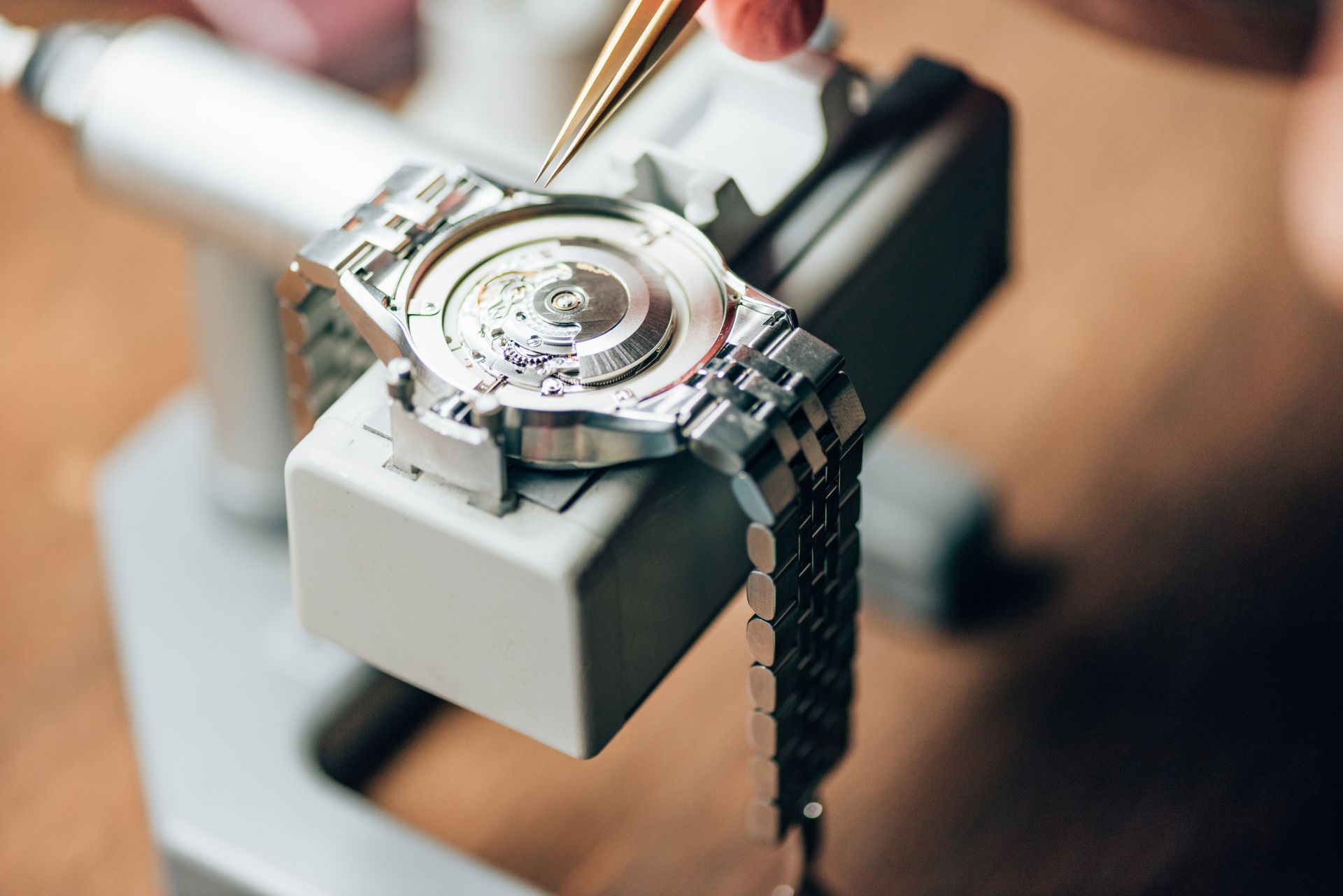 Gros plan d'une montre-bracelet argentée sur un présentoir, avec une personne floue en arrière-plan.