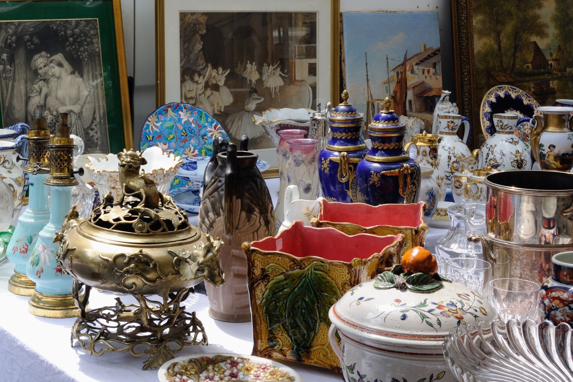 Assortiment de théières, de bocaux et de vaisselle décorative finement ouvragée, présentés sur une table dans une boutique ou un marché.