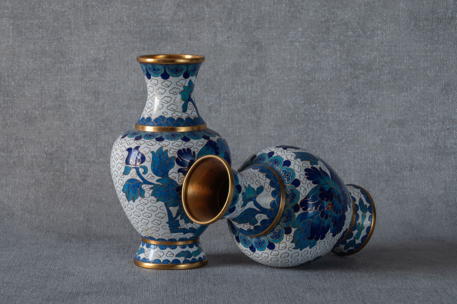 Vases décoratifs bleus et blancs à intérieur doré sur fond gris.