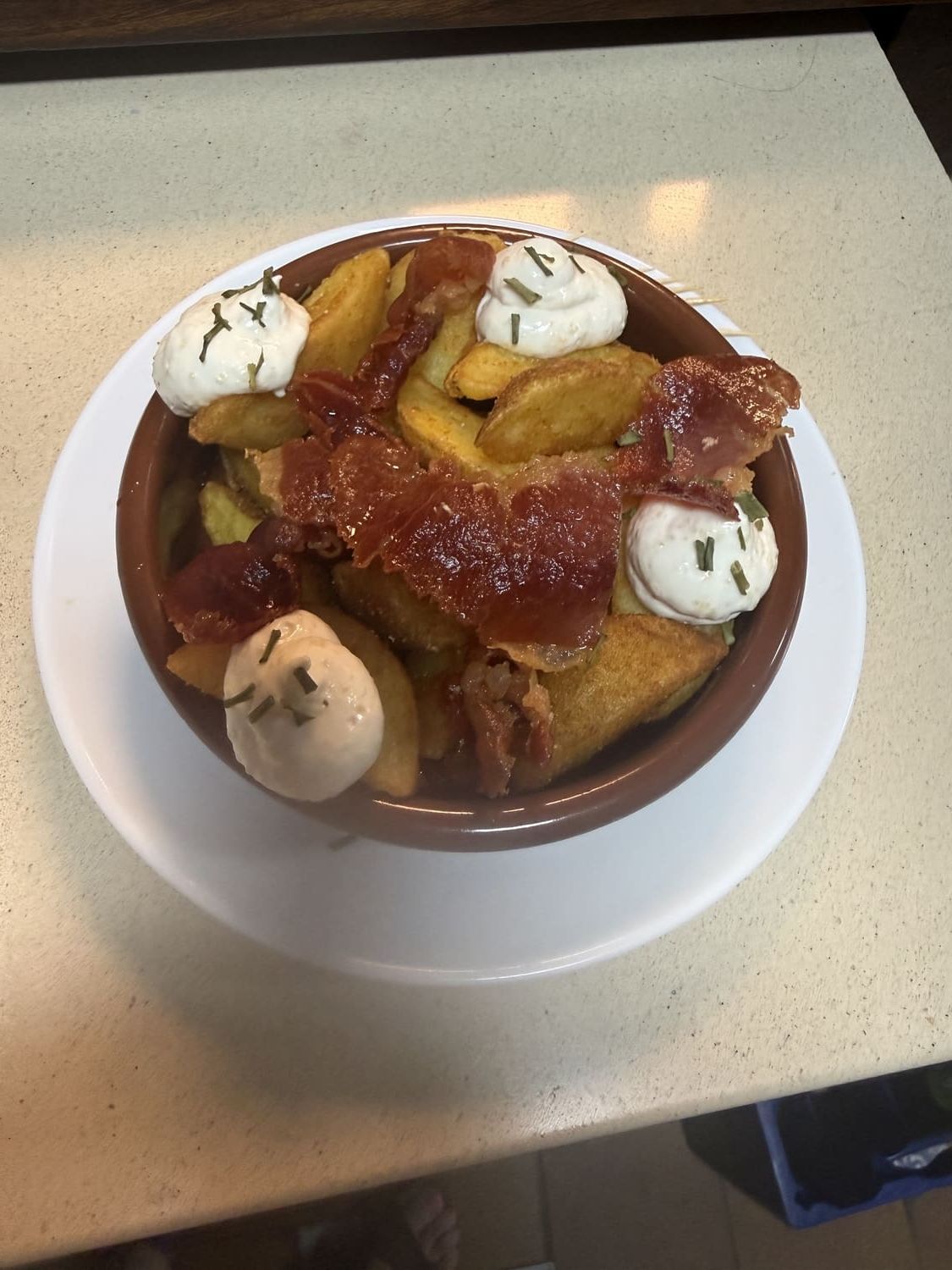 Bol de postre con fruta caramelizada y crema batida sobre un plato blanco.