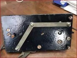 Un objeto negro con tornillos está sobre una mesa de madera.