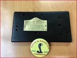 Una placa negra con una etiqueta de latón está sobre una mesa de madera.