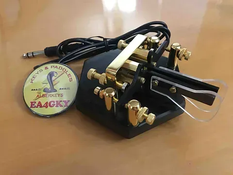 Un control remoto está sobre una mesa de madera al lado de una pegatina que dice ea4gky.