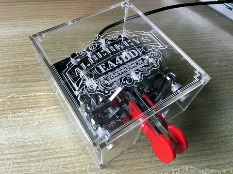 Una caja transparente con dos llaves rojas dentro está sobre una mesa de madera.