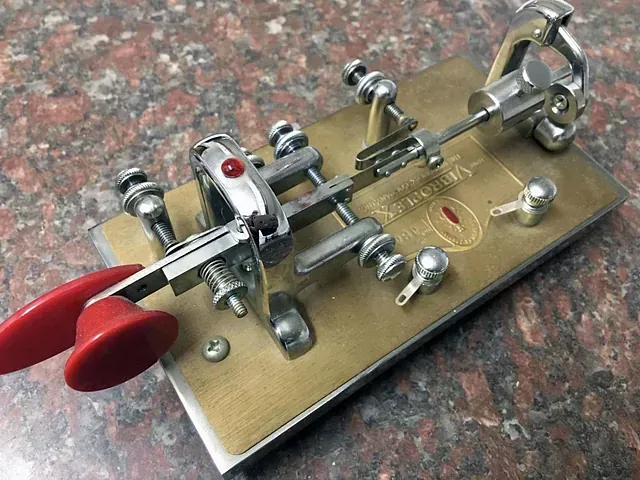 Un objeto de metal con un mango rojo está sobre una mesa.